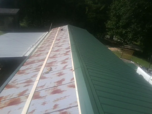 Old rusted panels beside newly installed green metal roofing — Wind Damage Roof Repair by Roofing Brothers in Closter