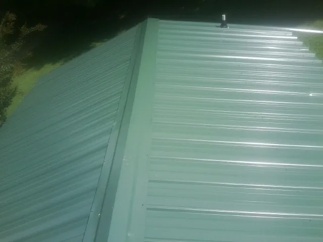 New green metal panels meeting at the ridge of a roof — Flat Roof Repair work by our crew in Closter