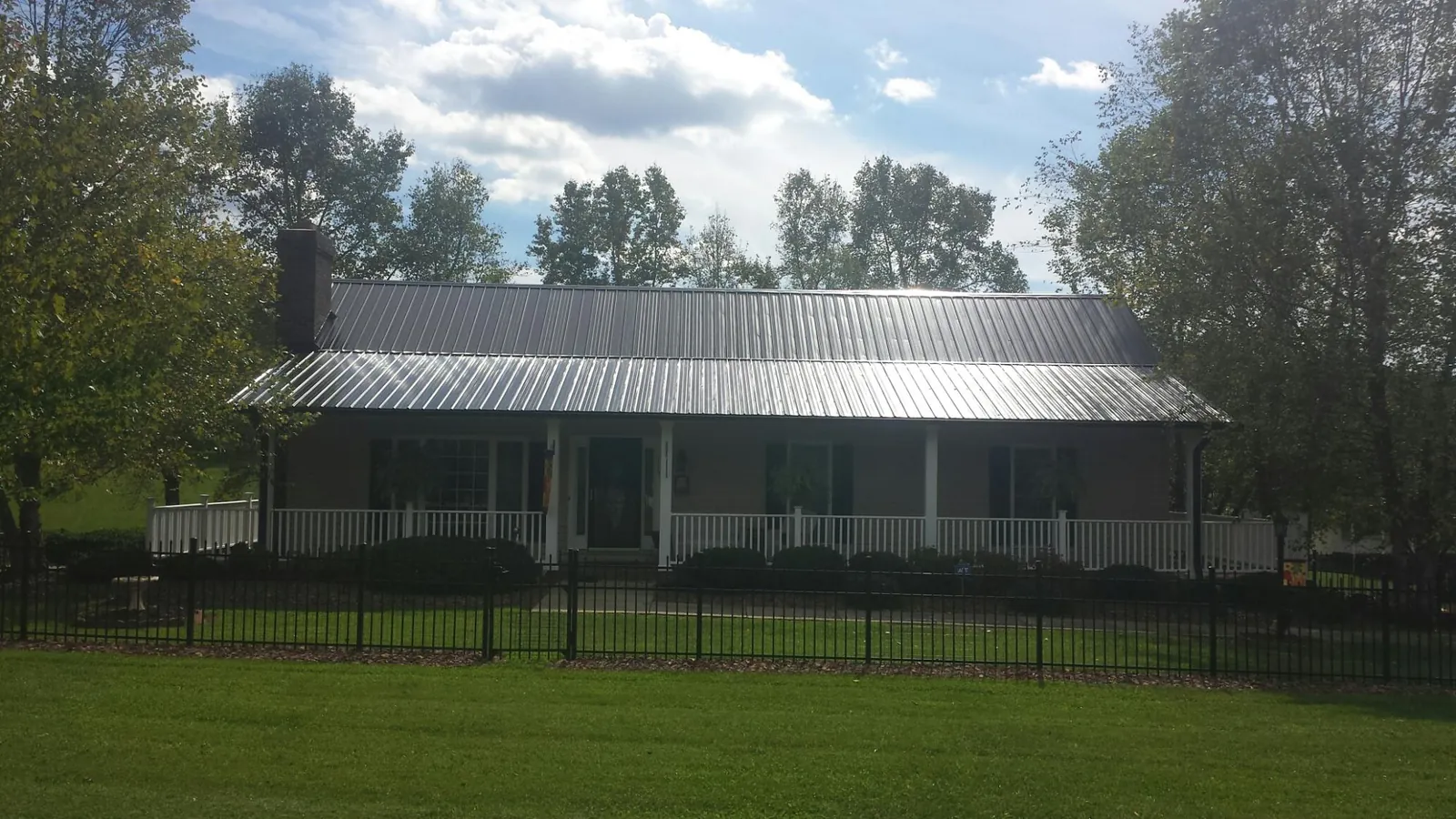 Gray metal roof on a brick ranch with a full width front porch — Gutter Guard Installation work by our crew in Closter