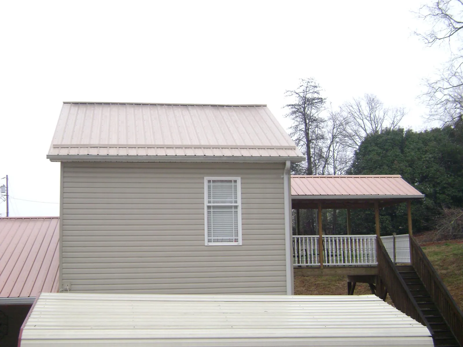 Tan metal roofs on a two story addition and attached porch, from a Roof Replacement job in Closter